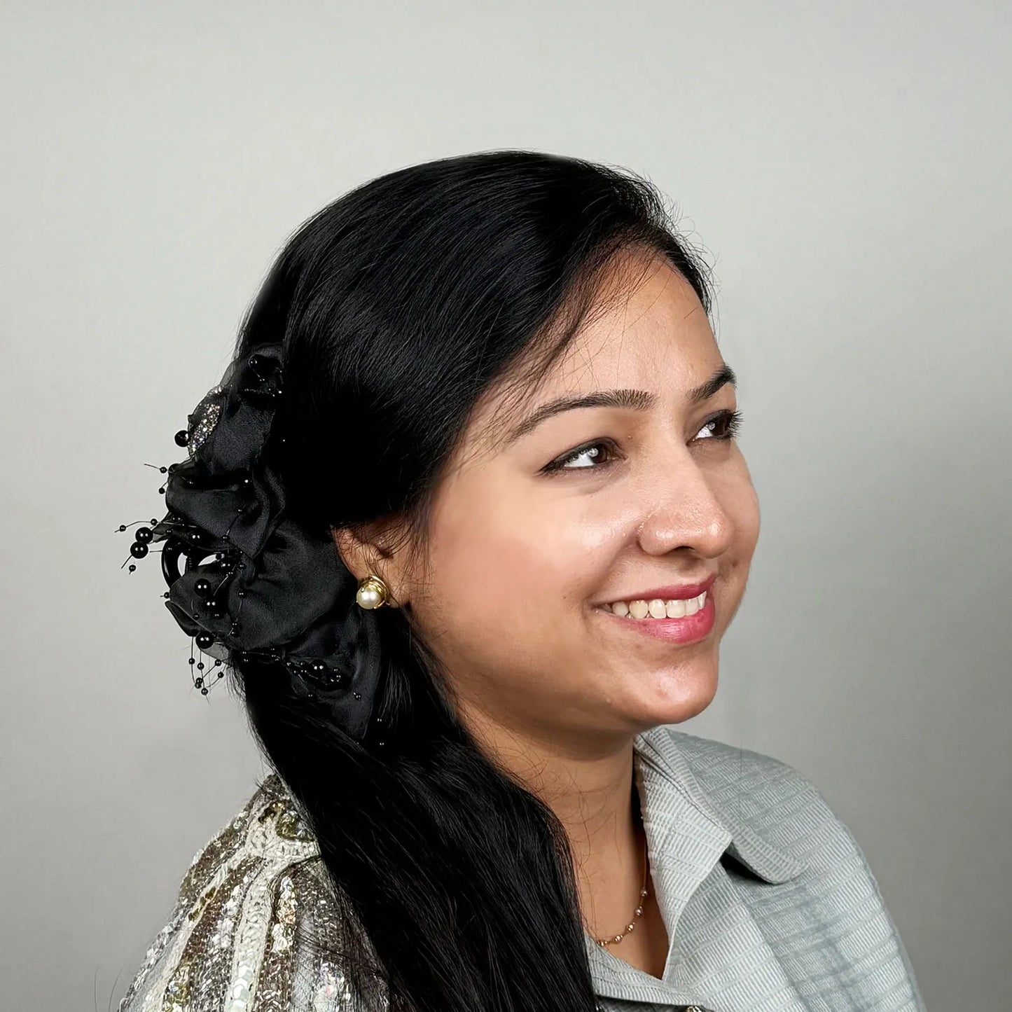 Woman with decorative black hair claw clutcher against a gray background