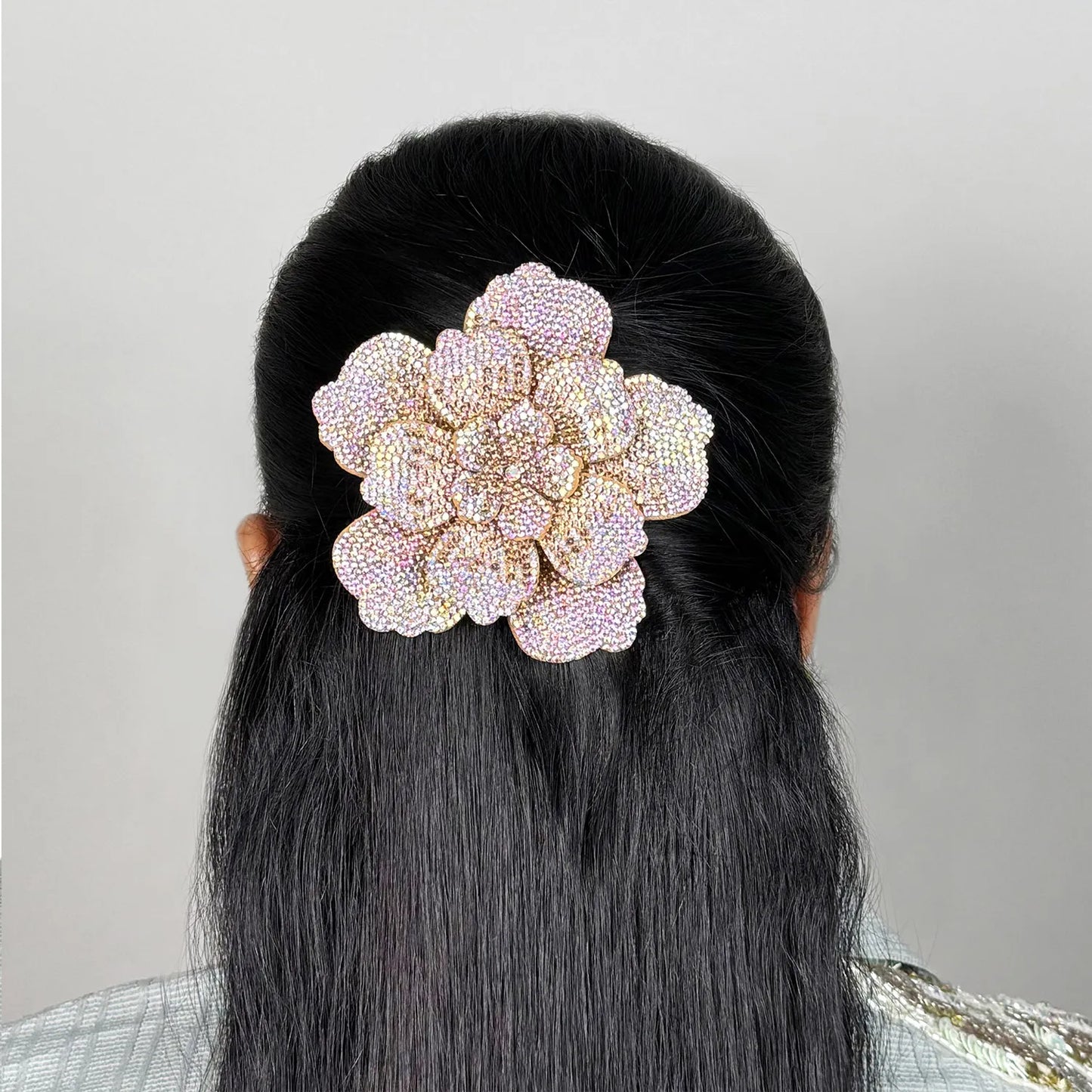 Person with black hair wearing a decorative floral side hair comb against a neutral background