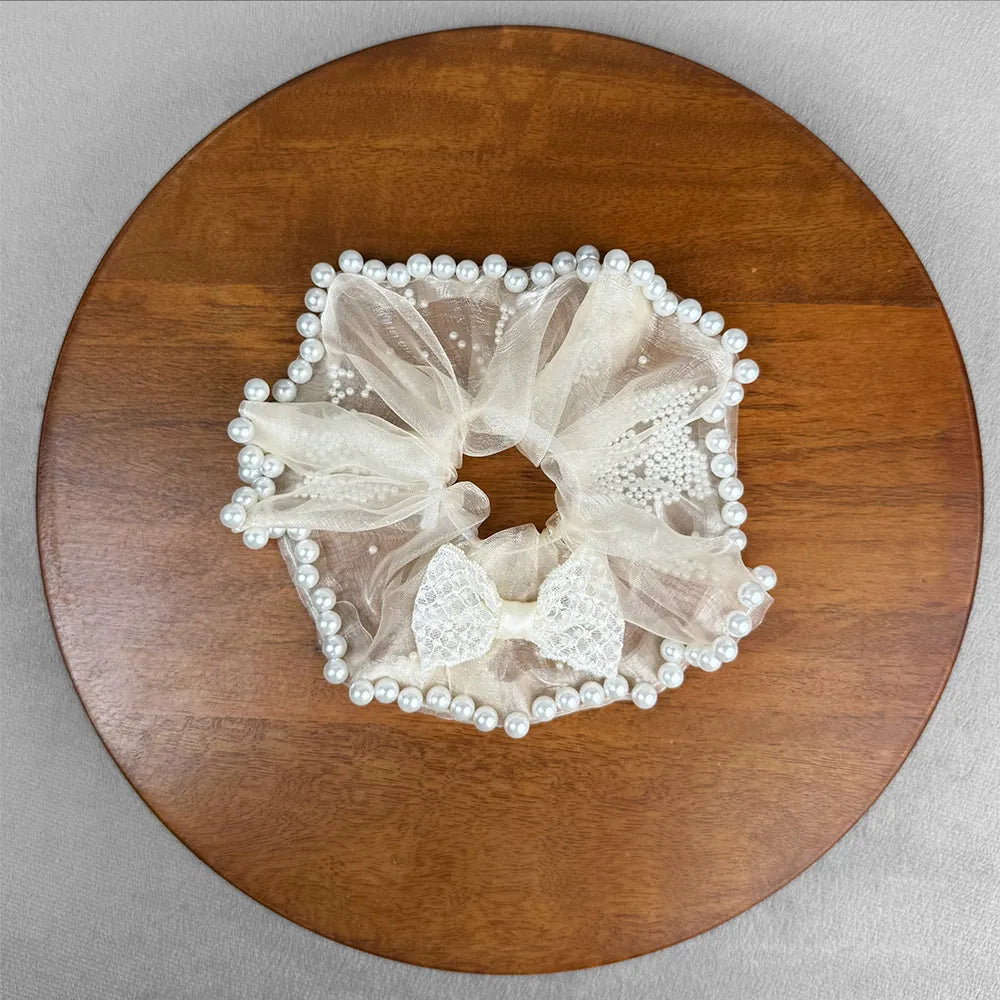 White lace scrunchie with pearls on a wooden surface