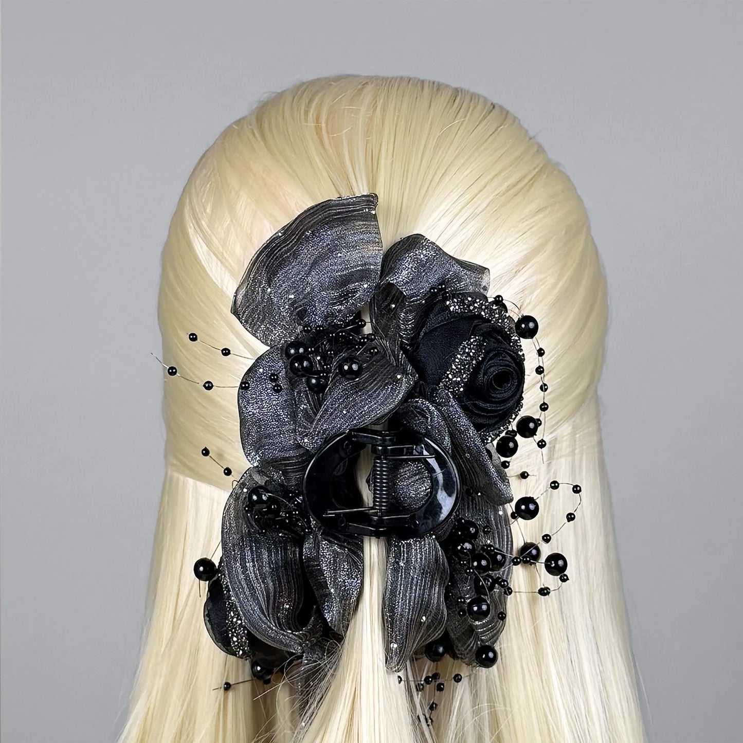 Blonde wig with a decorative gray floral hair claw clutcher on a gray background