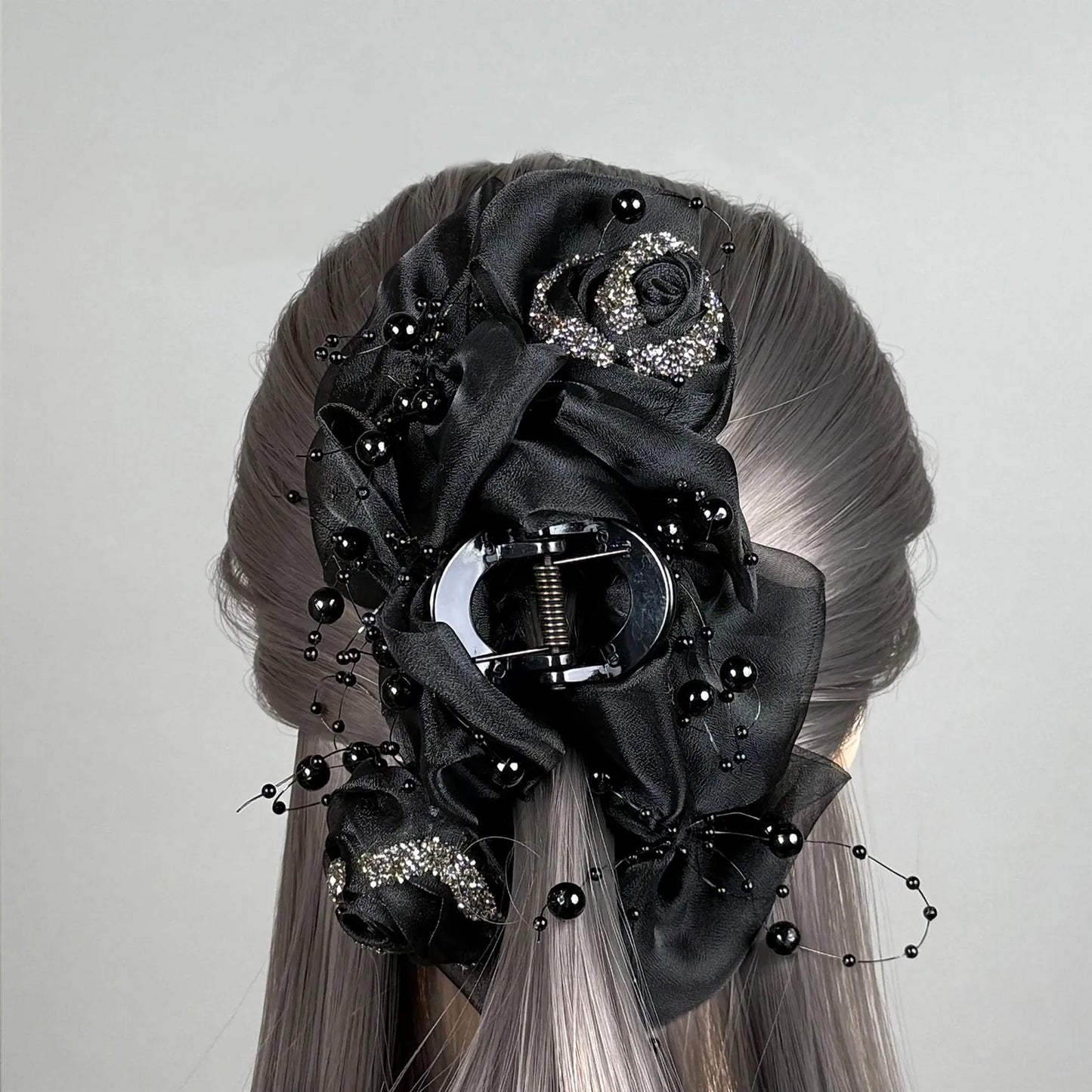 Wig with a decorative black floral hair claw clutcher on a gray background