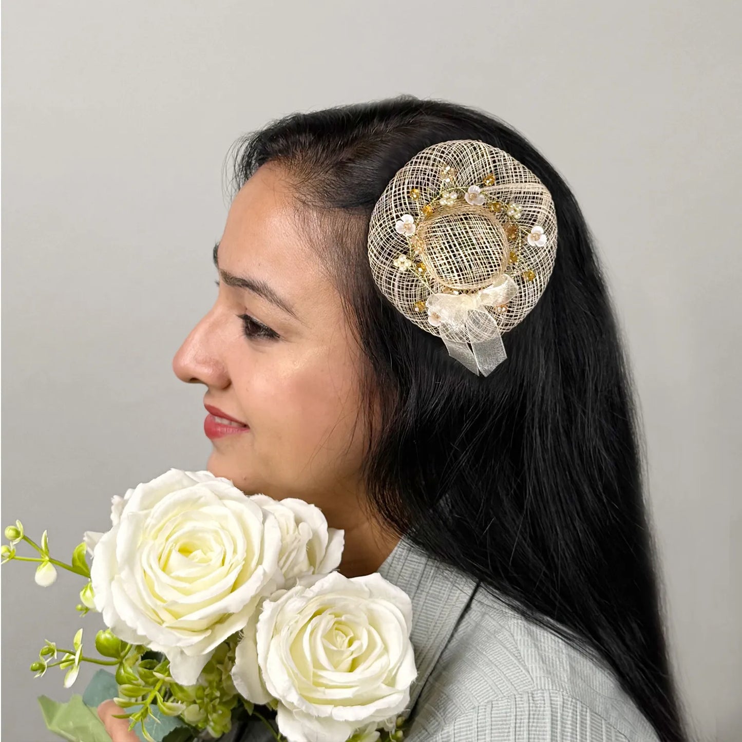 Women wearing golden fascinator hair clip with floral embellishments and flowers in hand