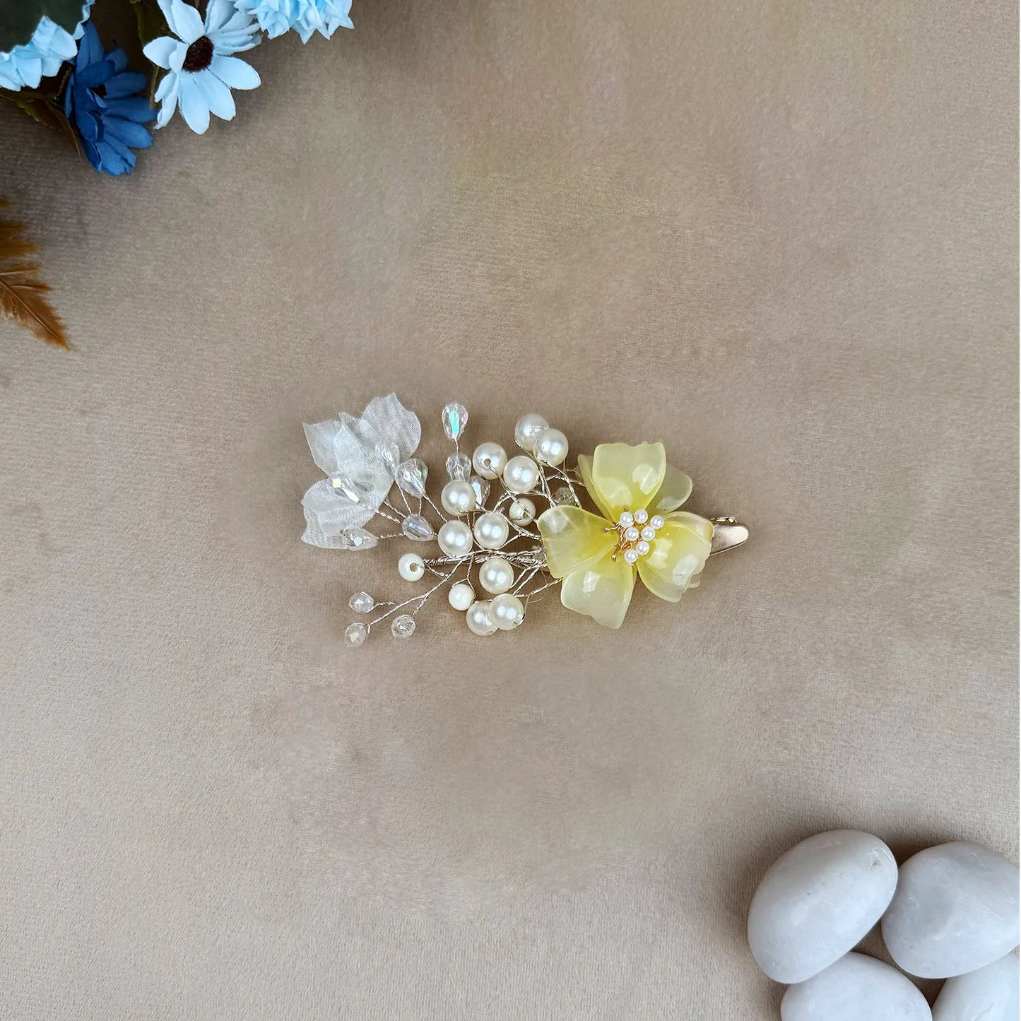 Hair clip with yellow flower and pearls on a beige background