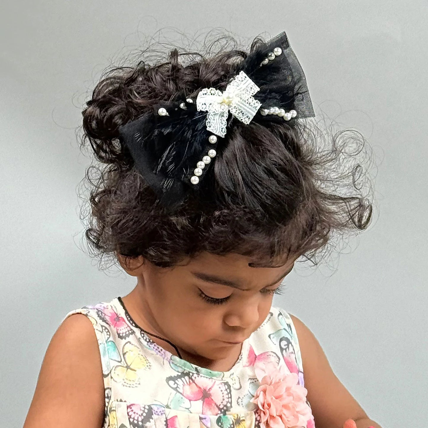 Child with decorative hair bow headband on a plain background
