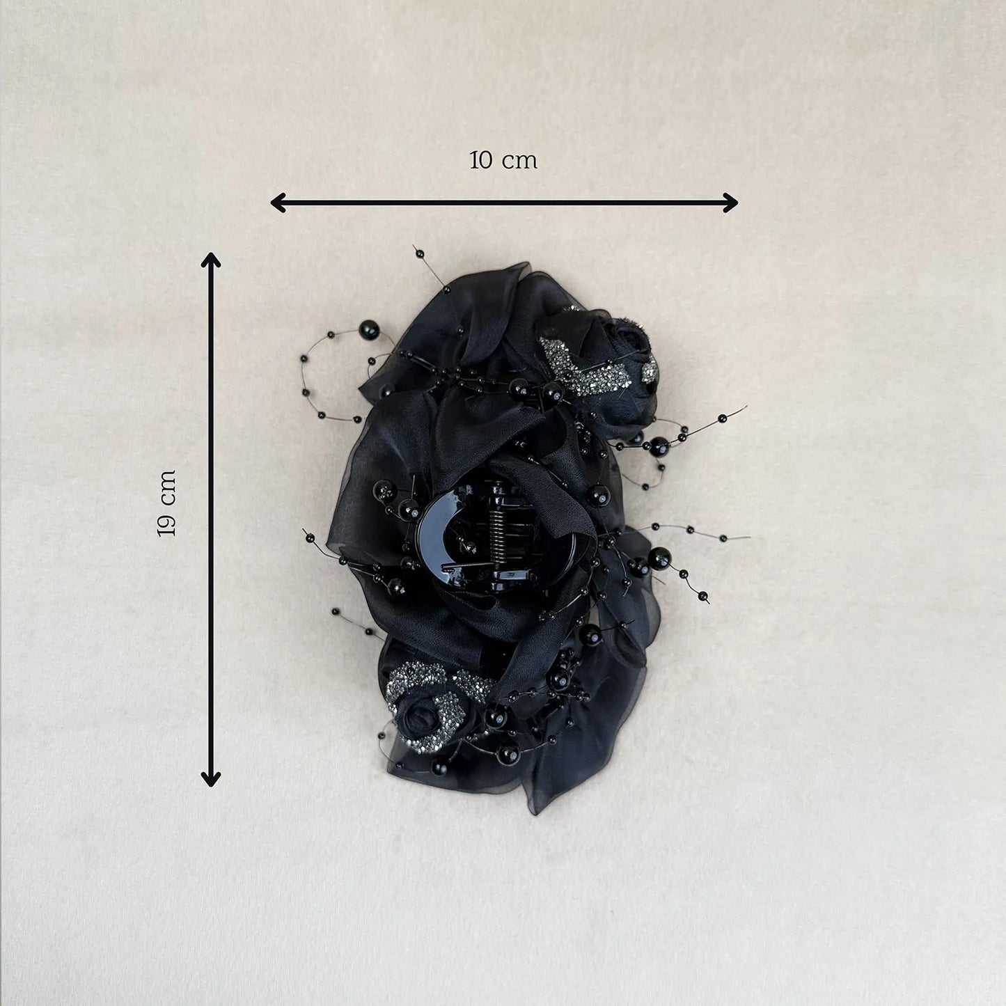 Black floral hair clip with measurements on a light gray background