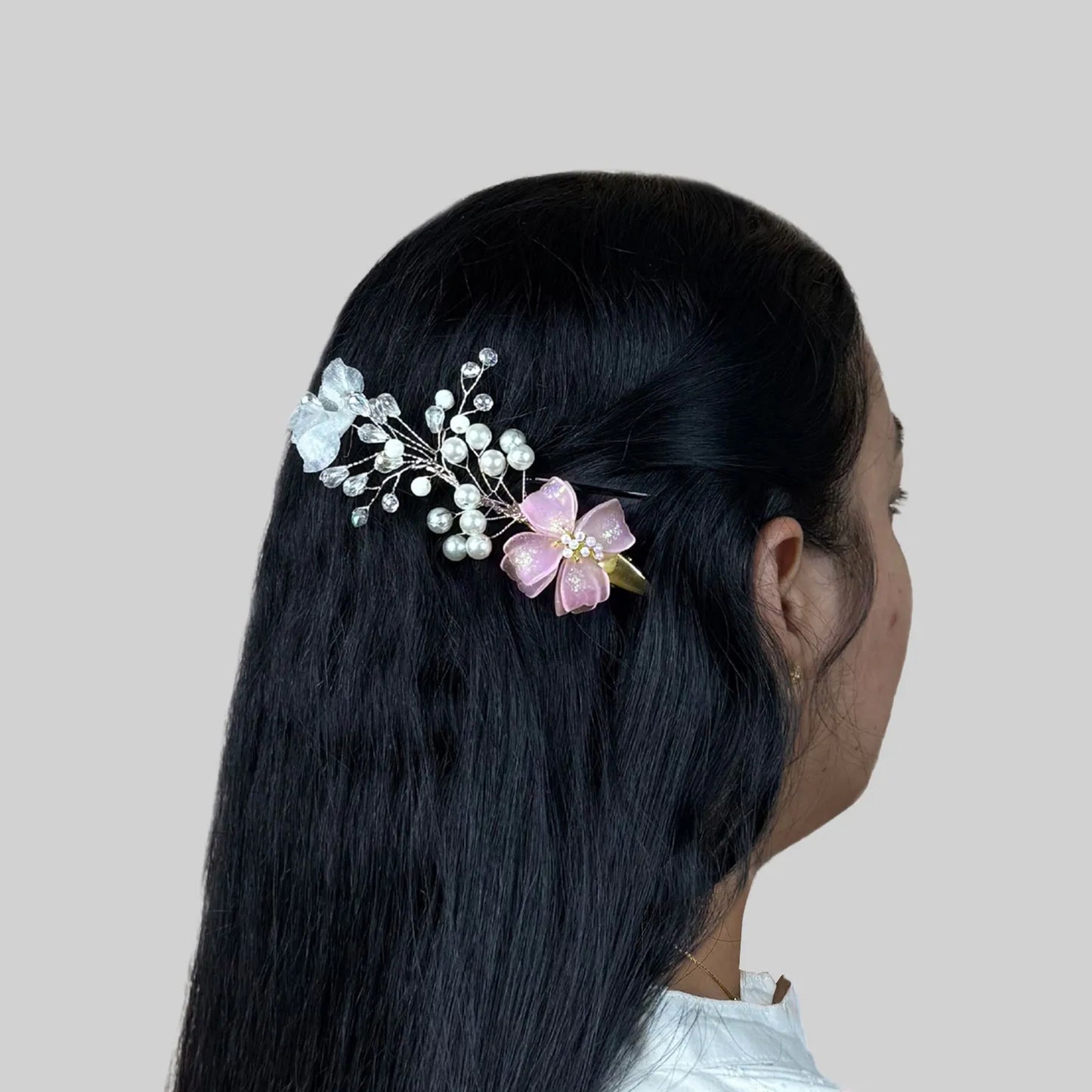 Woman with floral pink hair accessory on a plain background
