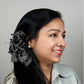 Woman with decorative gray hair claw clutcher against a gray background