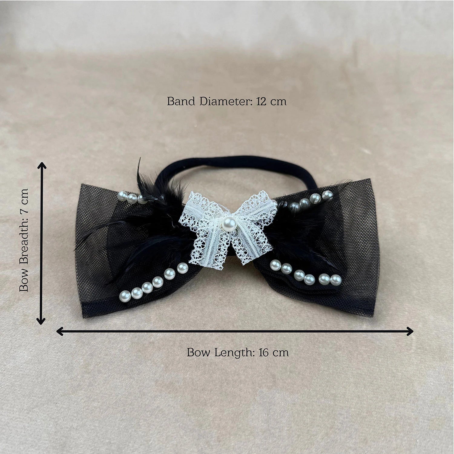 Black bow hair accessory with white lace and pearls, shown with measurements on a beige background.