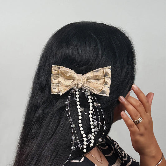 Hair bow with decorative elements on black hair against a gray background