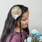 Girl wearing golden fascinator hair clip with floral embellishments