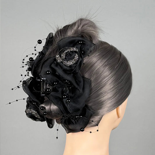 Mannequin head with intricate black floral hairpiece on a gray background