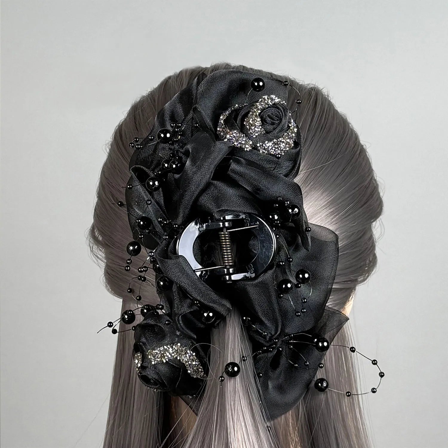 Wig with a decorative black floral hair claw clutcher on a gray background