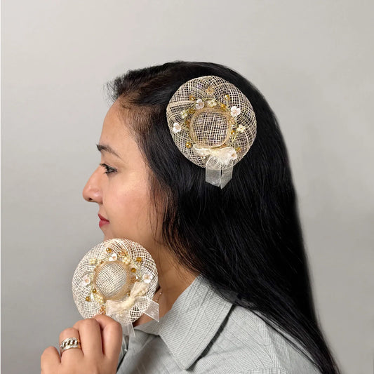 Women  wearing golden fascinator hair clip with floral embellishments with similar piece in hand