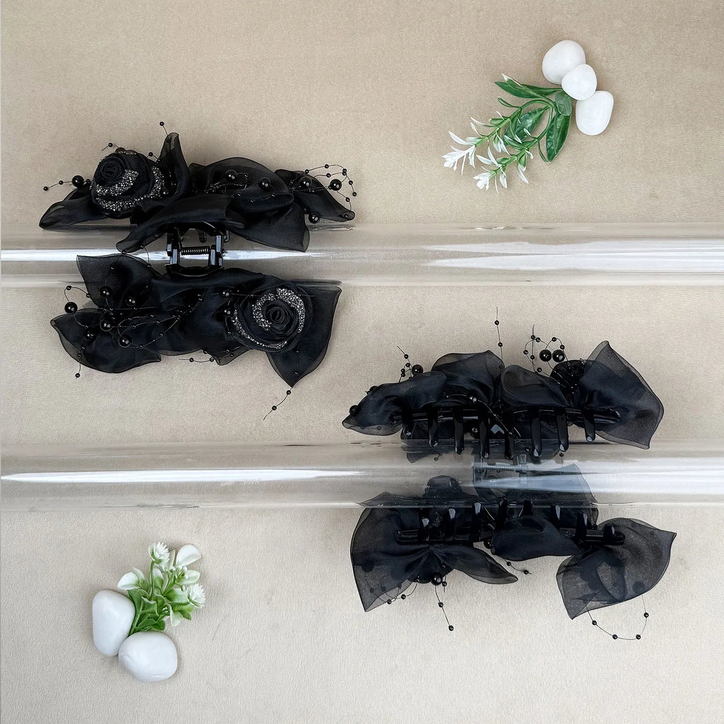 Black floral hair claw clips on a beige background with decorative elements.
