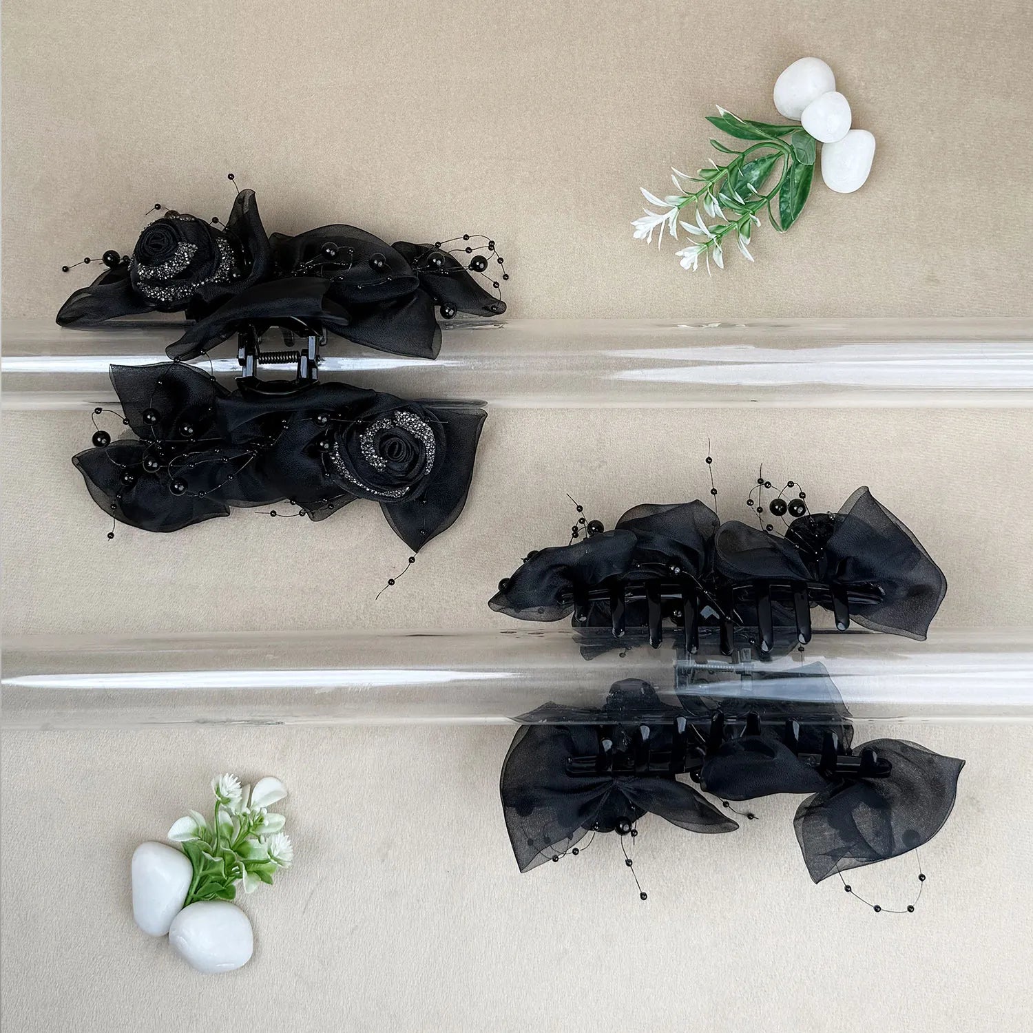 Black floral hair claw clips on a beige background with decorative elements.