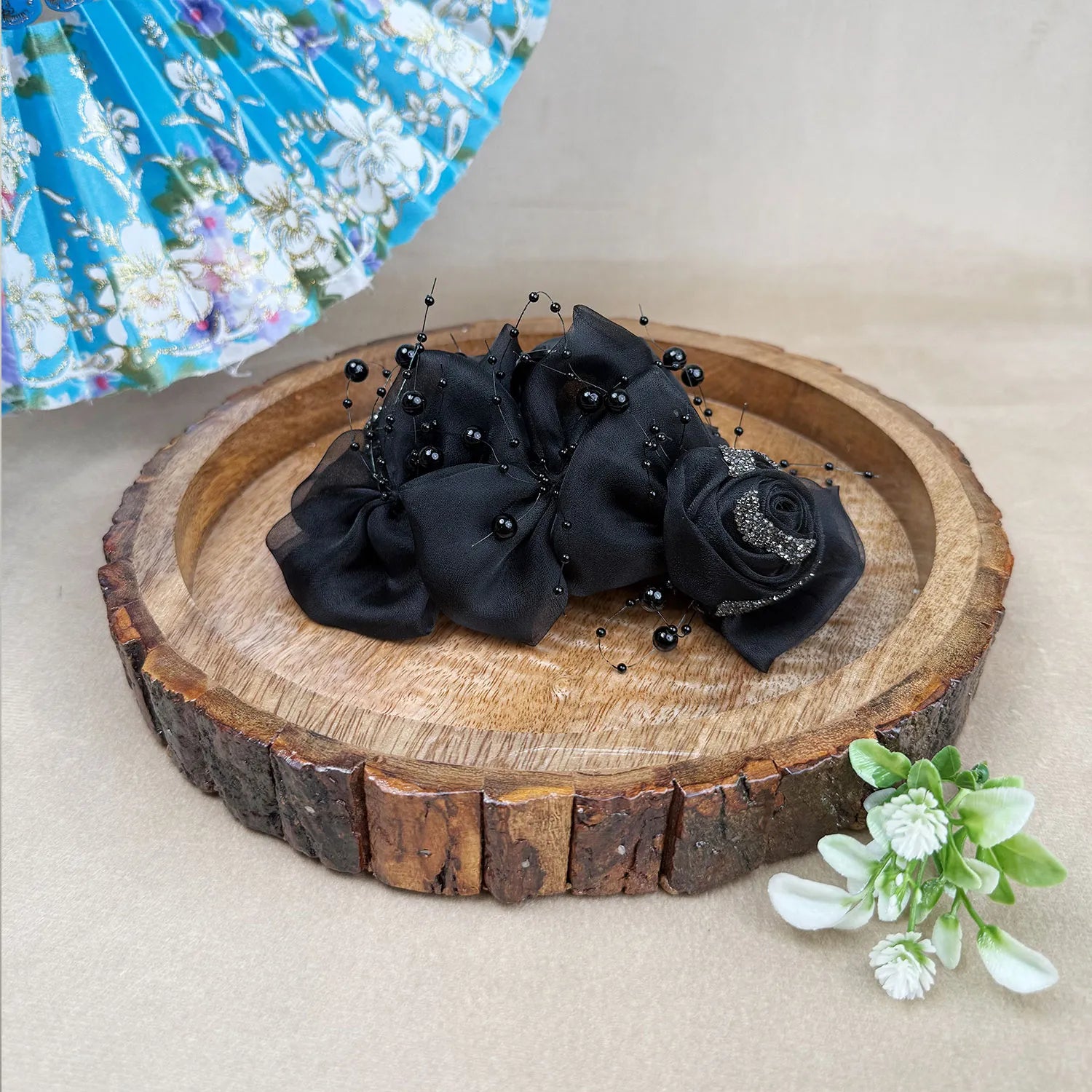Black decorative flower hair clutcher on a wooden slice with a floral background