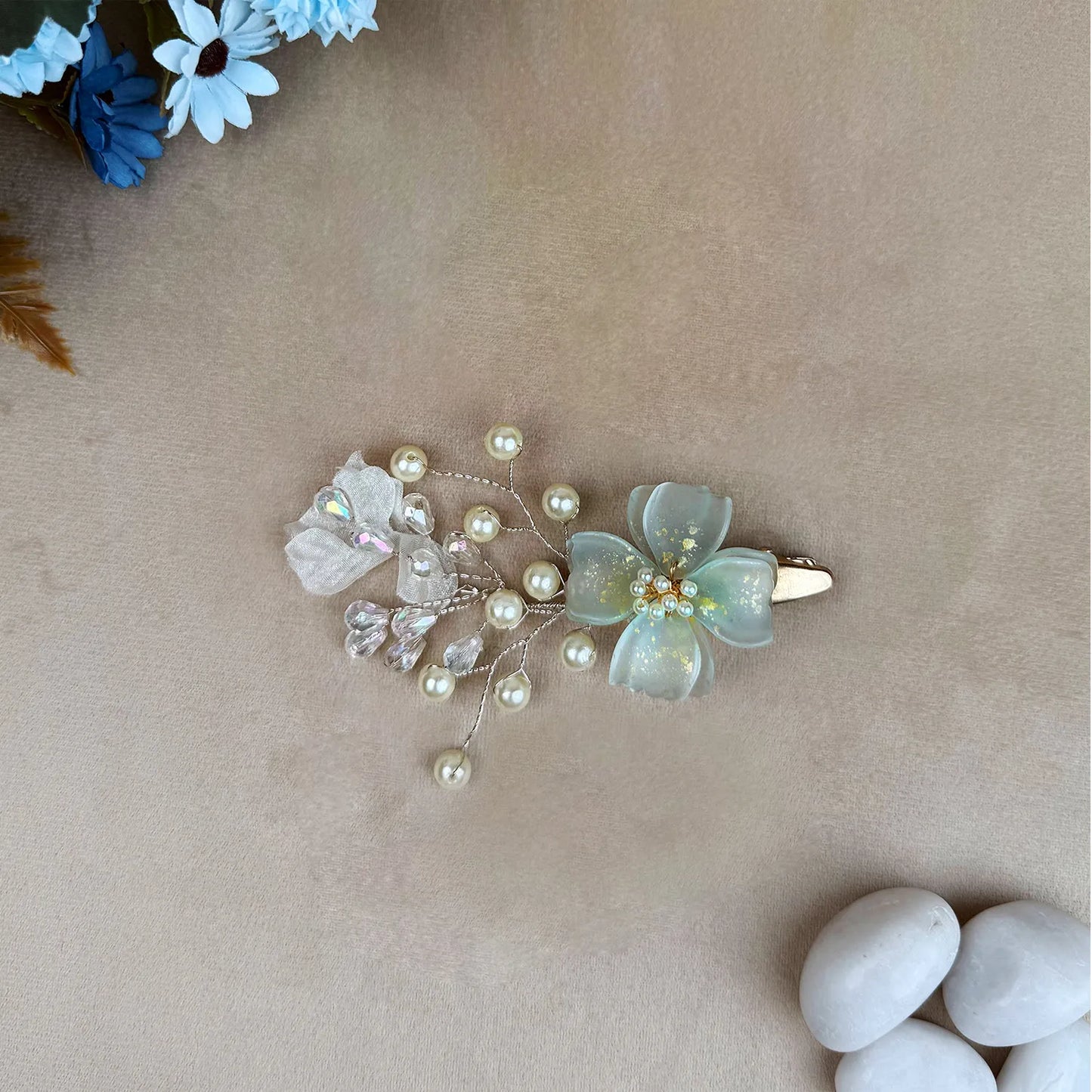 Hair clip with green flower and pearls on a beige background