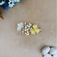 Hair clip with yellow flower and pearls on a beige background