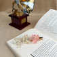 Decorative hair clip with pink flower and pearls on an open book with a vintage gramophone in the background.