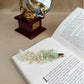 Decorative hair clip with green flower and pearls on an open book with a vintage gramophone in the background.