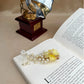 Decorative hair clip with yellow flower and pearls on an open book with a vintage gramophone in the background.