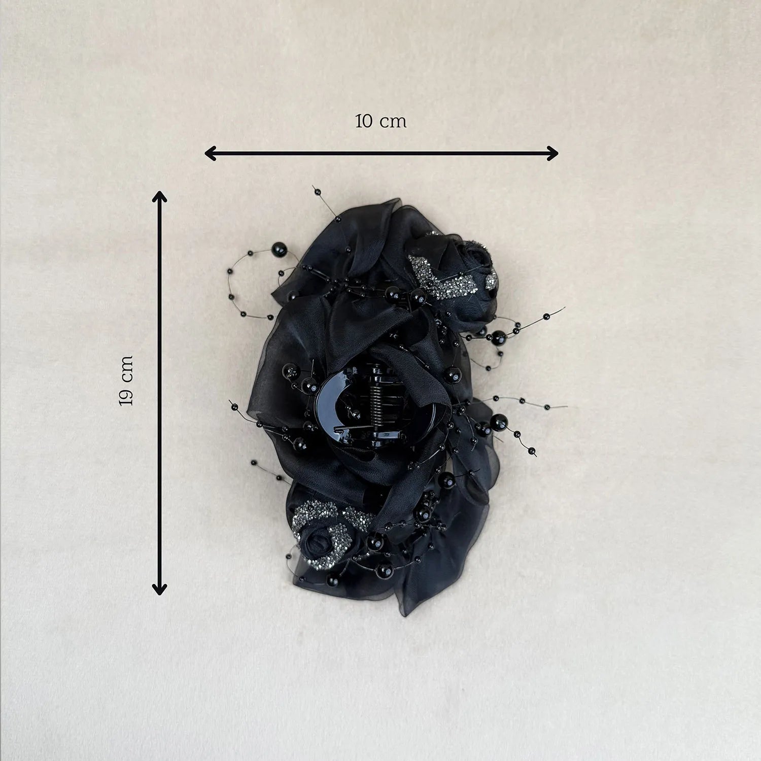 Black floral hair clip with measurements on a light gray background
