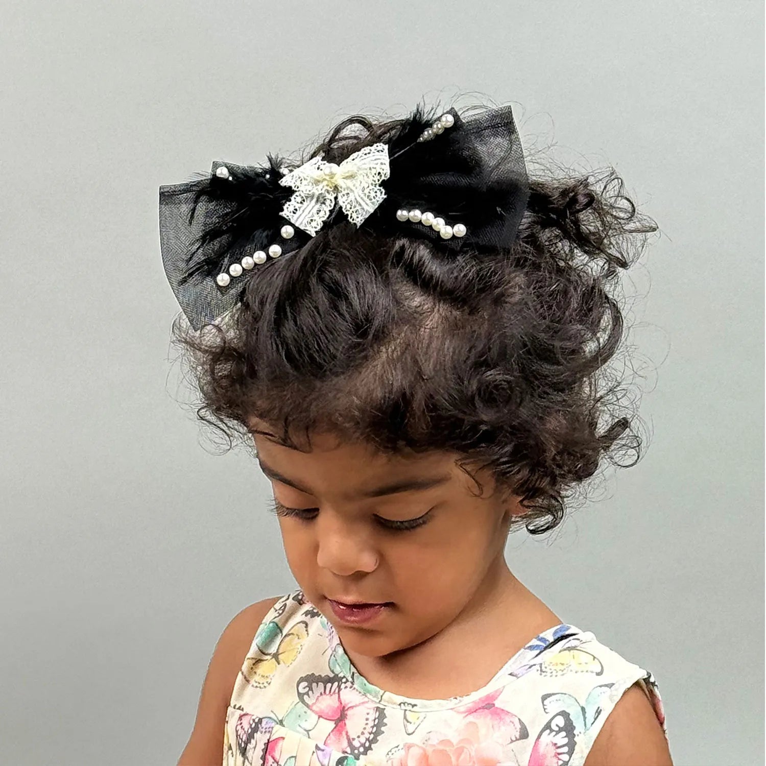 Child with decorative hair bow headband on a plain background