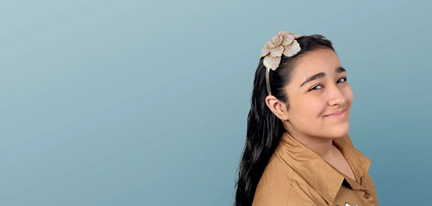 Young girl wearing a floral headband against a light blue background